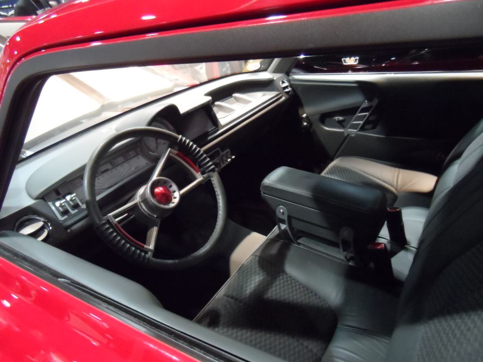 Interior of a red classic car, showing a custom steering wheel and dashboard.