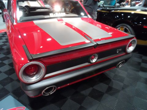 1971 Ford Ranchero - The rear of a bright red custom classic car with silver racing stripes is shown. Visible modifications include a carbon fiber accent on the…