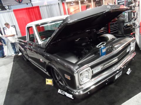 1971 Ford Ranchero - A dark gray 1971 Ford Ranchero pickup truck is on display with its hood open, revealing the engine. The truck has a white roof and is parke…