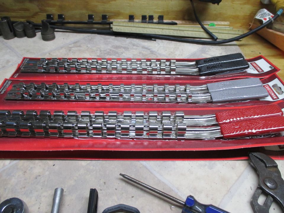 Three Craftsman socket rail sets in red trays on a workbench