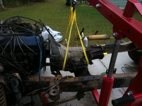 1979 Ford Bronco - Engine and transmission assembly being removed from a vehicle using an engine hoist.