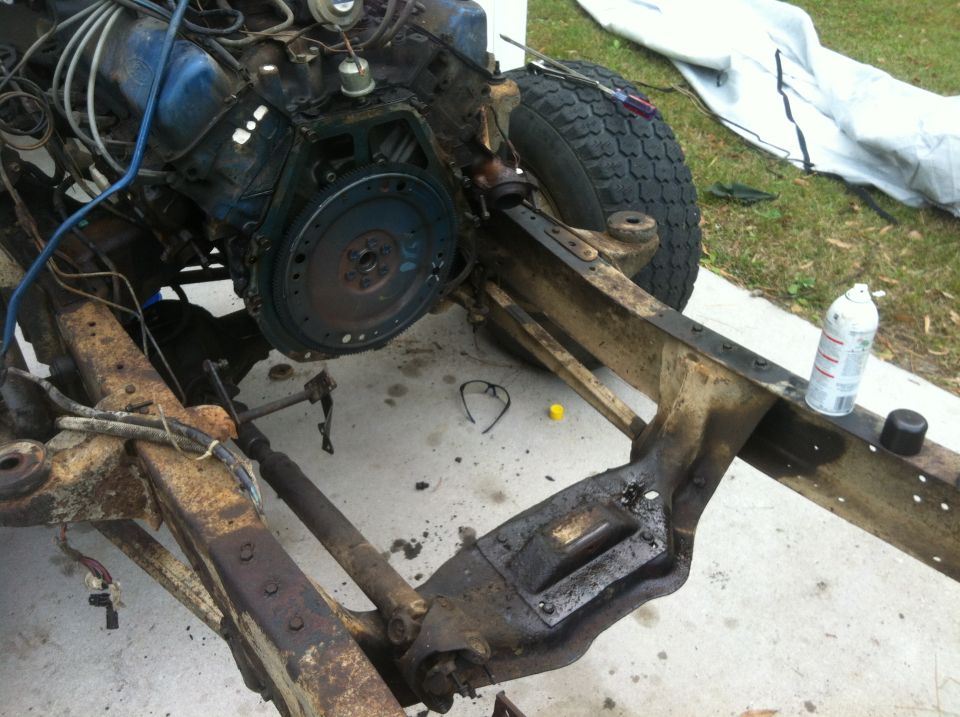 Vehicle frame with engine partially installed, showing suspension and drivetrain components