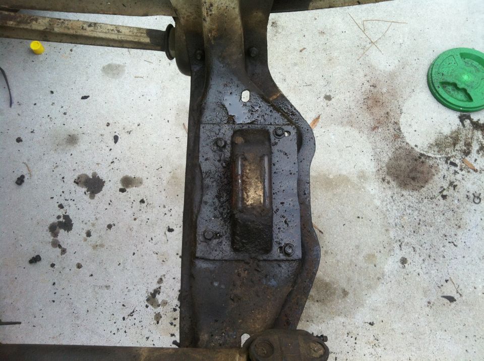 Vehicle frame component with bolts and grease stains on concrete