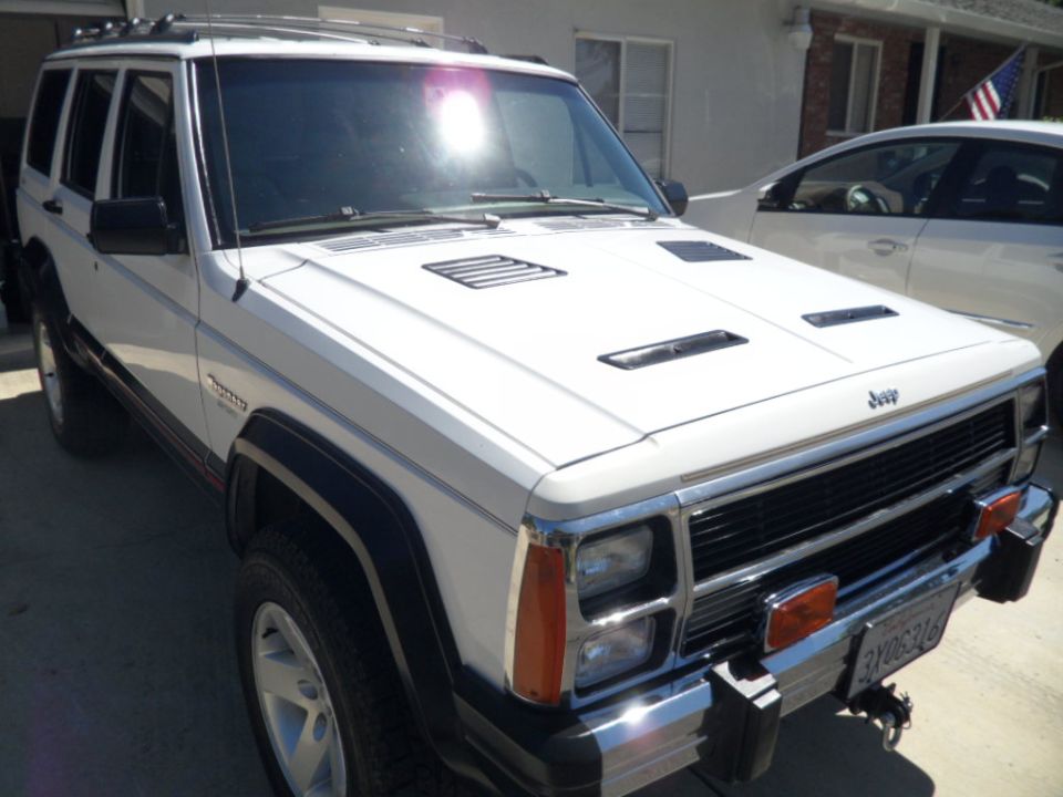 White 1994 Jeep Cherokee with aftermarket hood vents parked outside