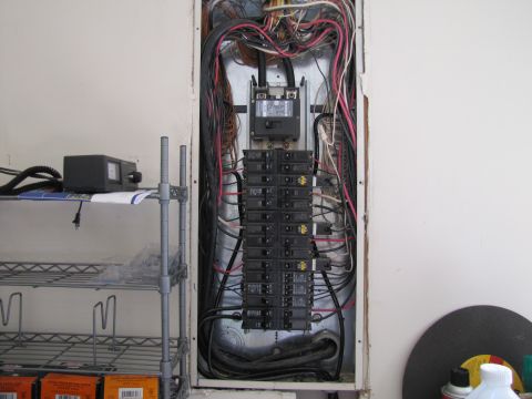 1995 Ford Bronco - This image shows an electrical panel with many wires and circuit breakers. To the left, there is a metal shelf unit with some items on it,…