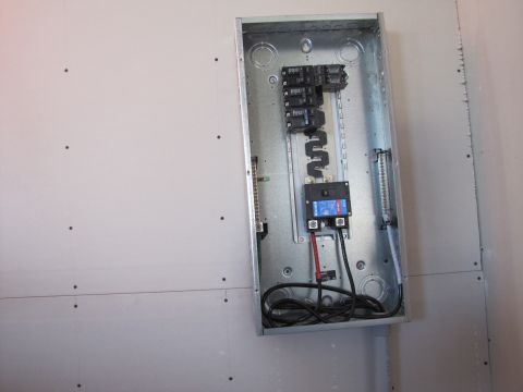 1995 Ford Bronco - An open electrical panel box is mounted on a wall covered with drywall. The panel contains circuit breakers and wiring.