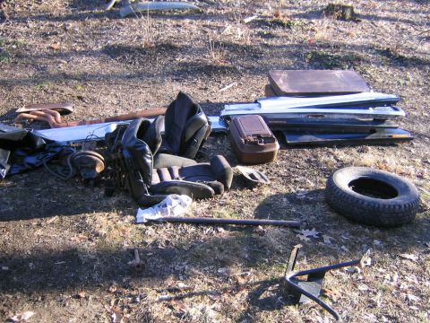 1978 Ford Bronco - Various car parts are piled on the ground, including seats, doors, and a spare tire.