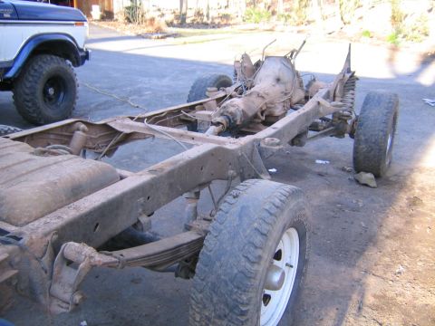 1978 Ford Bronco - Frame and transmission of a Ford Bronco, with another Bronco in the background.
