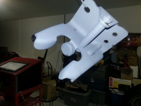 1994 Ford Bronco - Photograph of a primed steel bracket in a shop, not a technical document.