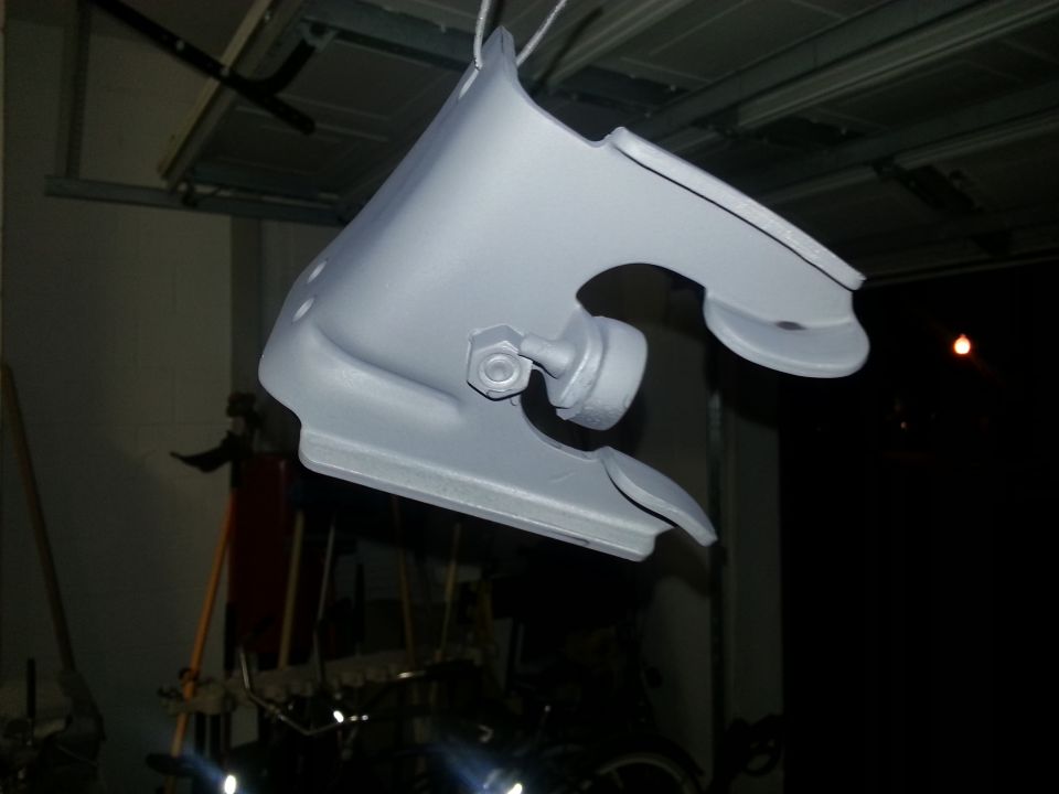 Gray painted automotive part hanging from a wire in a garage