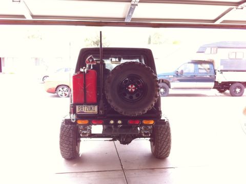 1987 Suzuki Samurai - Rear view of a red 1987 Suzuki Samurai, showing its spare tire and tow hitch.