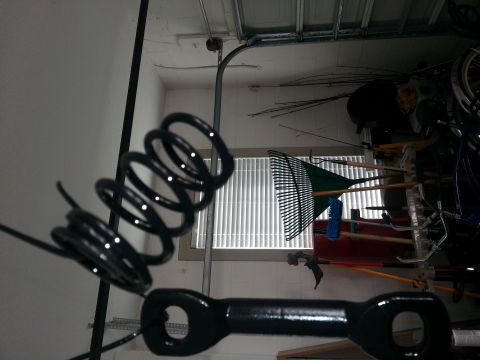 1994 Ford Bronco - Garage scene with a coil spring and tow hitch part, plus gardening tools and a bicycle.