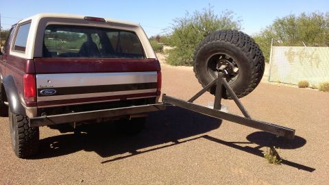 1996 Ford Bronco - The rear of a Ford Bronco is shown with a custom-built spare tire carrier mounted to its bumper.