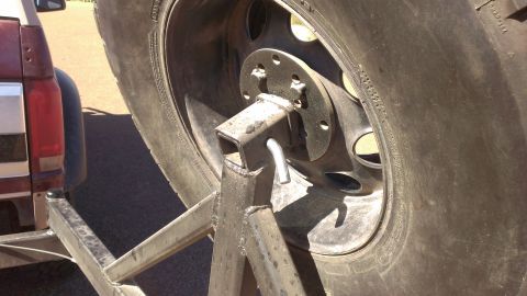 1996 Ford Bronco - A spare tire is mounted on a trailer hitch, with the rear of a red and silver truck visible in the background.
