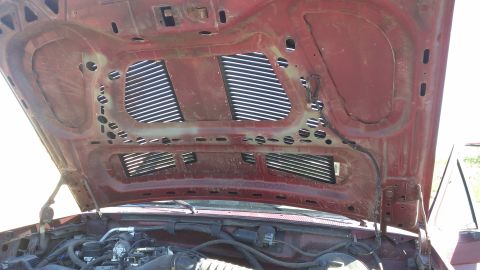 1996 Ford Bronco - The underside of a vehicle's hood, revealing vents and a glimpse of the engine compartment.