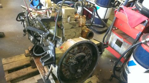 1996 Ford Bronco - Engine assembly, likely removed from a vehicle, sits on wooden pallets in a workshop environment.