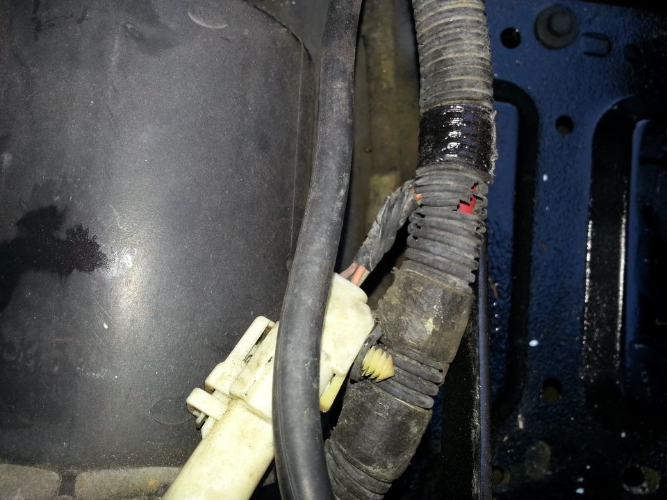 Wiring harness with black corrugated tubing and a white connector, part of a 1994 Ford Bronco