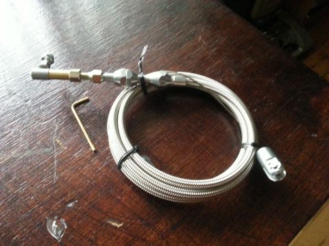 1981 Ford Bronco - A braided fuel line and an Allen wrench are shown on a wooden table. The line appears to be a replacement part.
