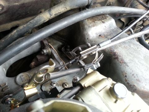 1981 Ford Bronco - Close-up view of carburetor linkage, throttle cable, and spring mechanism.