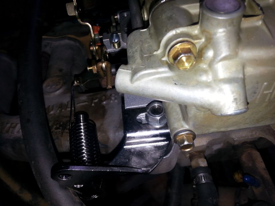 Carburetor with linkage and spring, chrome bracket, and engine block