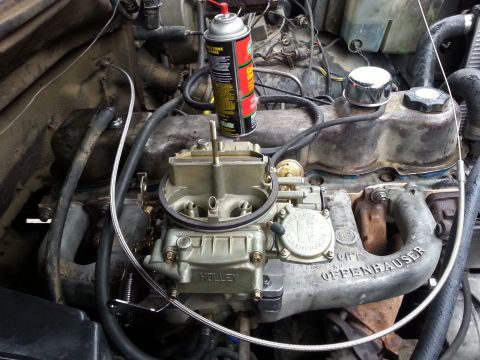 1981 Ford Bronco - Close-up of a vehicle's engine bay, focusing on the carburetor and intake manifold with a can of lubricant nearby.