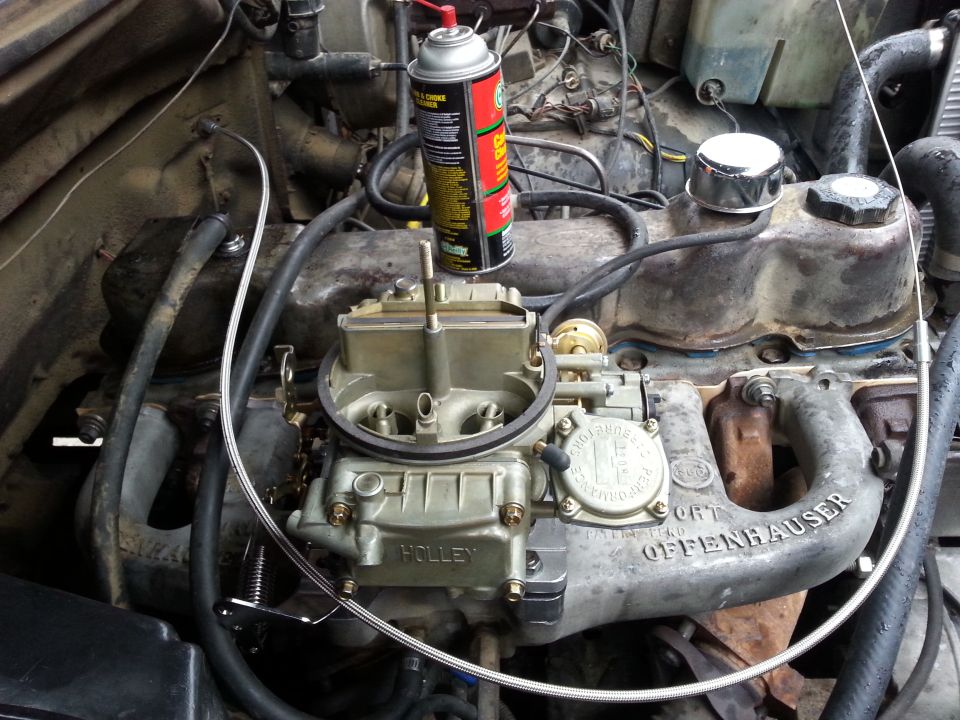 Engine bay with a Holley carburetor and an Offenhauser intake manifold. Can of spray lubricant sits on top