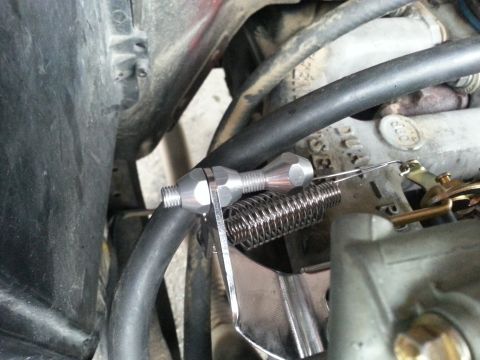 1981 Ford Bronco - A close-up view of a throttle cable linkage and spring assembly on a carburetor.