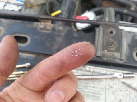 1981 Ford Bronco - A close-up shows a finger holding a small metal clip, with engine components and tools in the background.