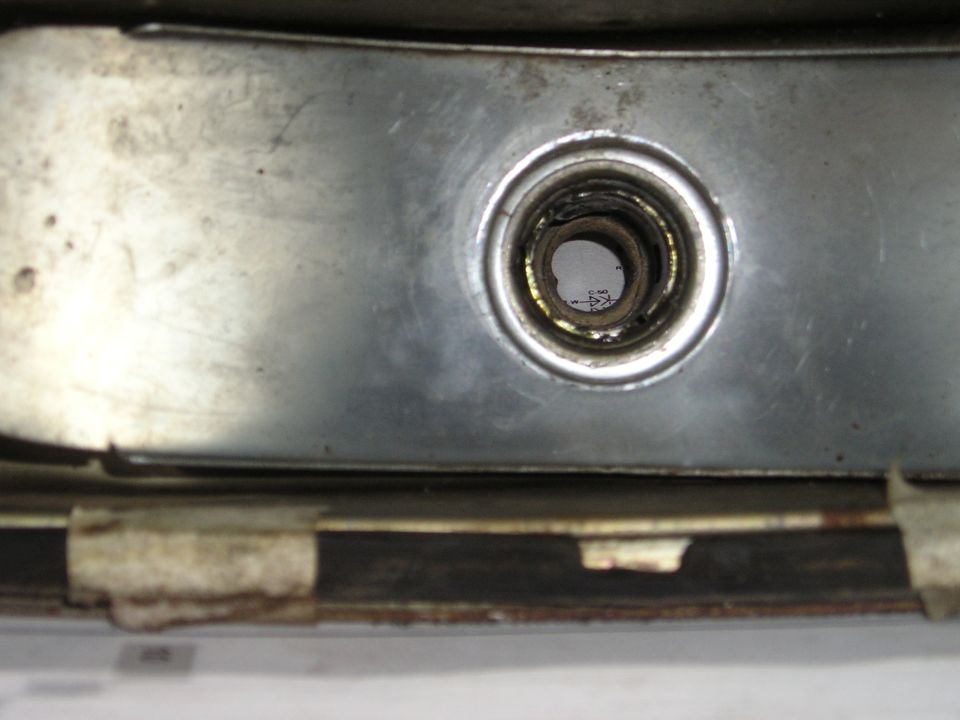 close-up of a metal bracket with a circular opening showing some internal components and text underneath