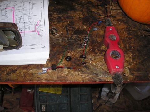 1975 Ford Courier - An electrical diagram is spread out on a workbench with various loose parts and a red tool.