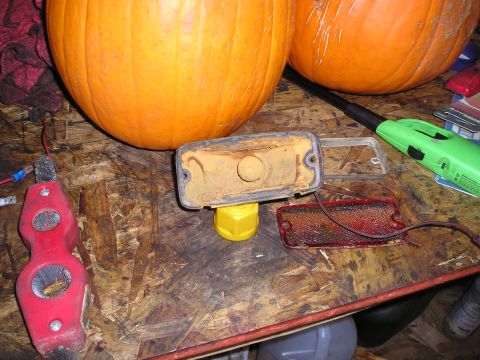 1975 Ford Courier - Disassembled vehicle light assembly and pumpkins on a workbench.