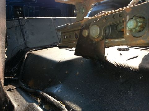 1994 Ford Bronco - Close-up of the seat mounting hardware and floor pan inside a vehicle.