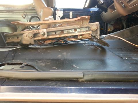 1994 Ford Bronco - The driver's seat has been removed, revealing the floor and interior components of a blue vehicle.