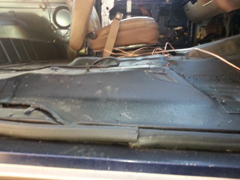 1994 Ford Bronco - The interior of a vehicle shows exposed flooring and wiring, with a single seat visible.