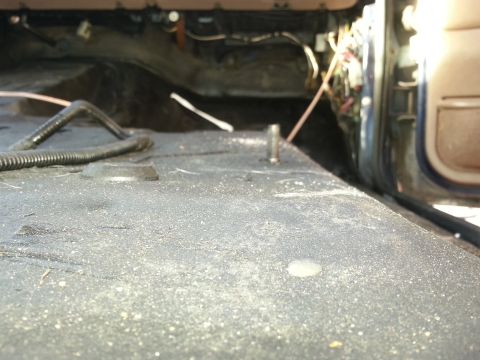 1994 Ford Bronco - The interior floor of a vehicle shows dust and exposed wiring near the open door.
