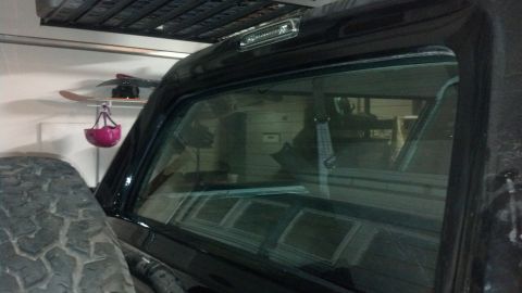 1995 Ford Bronco - The rear of a black SUV is visible, parked inside a garage with storage shelves above.