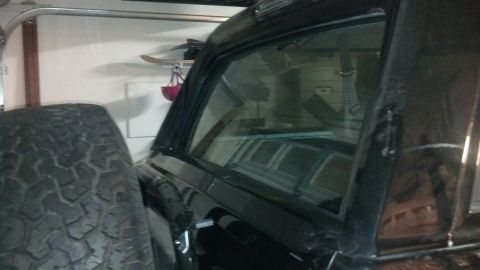 1995 Ford Bronco - Side view of a black SUV, possibly from the 1990s, with a spare tire in the foreground.