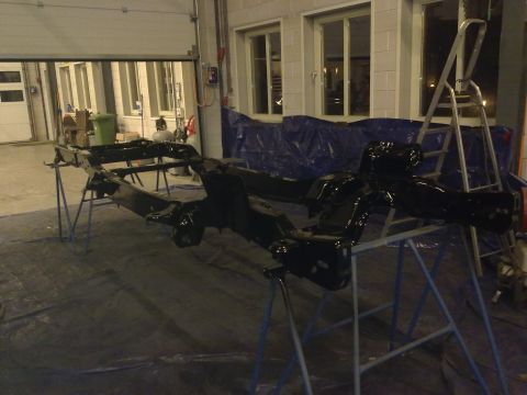 1984 Ford Bronco - A vehicle chassis is being worked on in a garage, with tools and tarps visible.