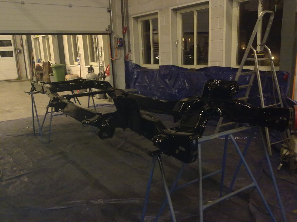 Black painted vehicle chassis on stands in a garage