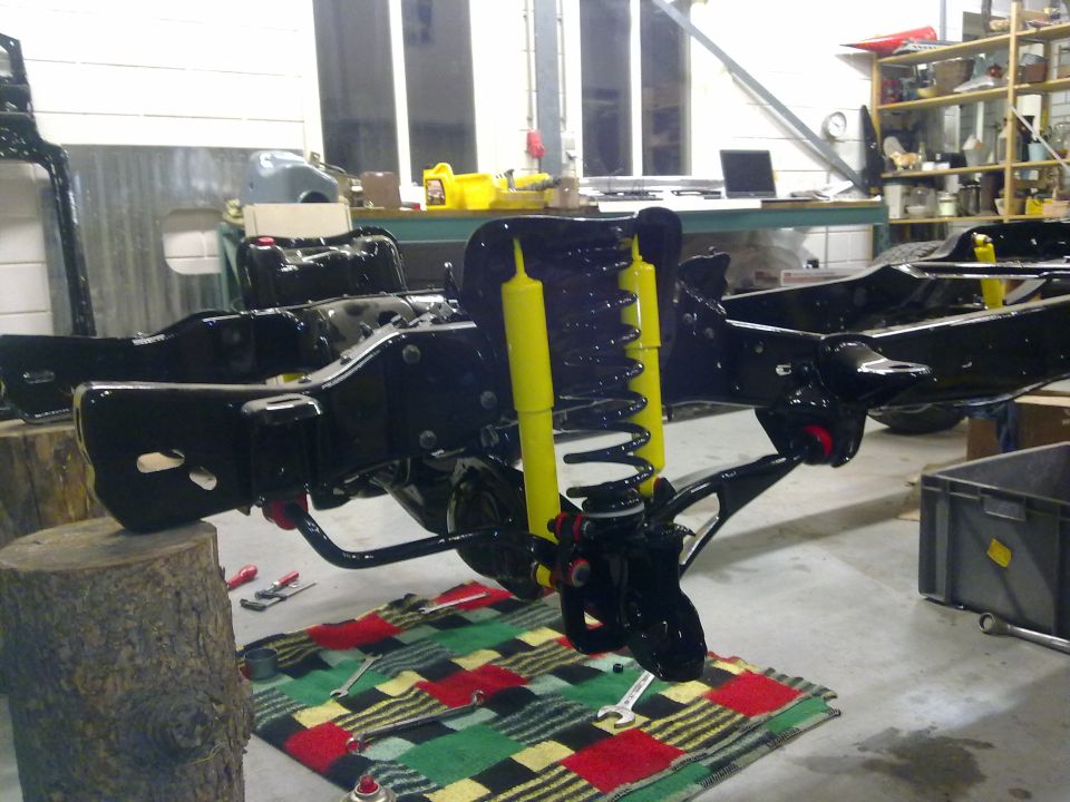 vehicle frame with yellow shocks and springs, tools on a blanket