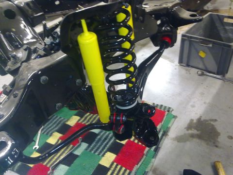 1984 Ford Bronco - Close-up of a vehicle's front suspension assembly, a yellow shock absorber and black coil spring during a rebuild.