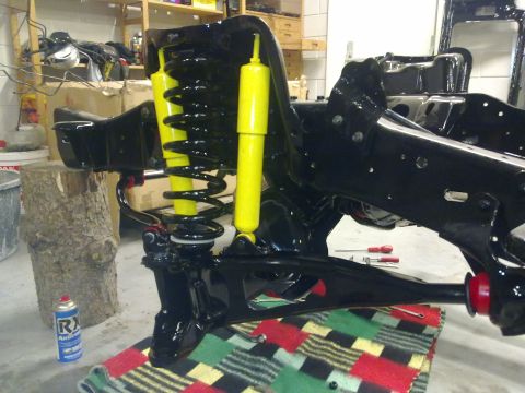 1984 Ford Bronco - The front suspension and frame components of a vehicle are shown during a rebuild process.