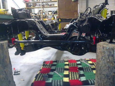 1984 Ford Bronco - Chassis and suspension components are visible during a rebuild, with yellow shocks and red sway bar mounts.