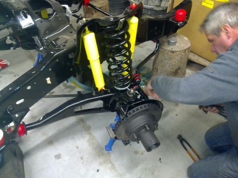 1984 Ford Bronco - A mechanic works on the front suspension of a vehicle during a chassis rebuild.