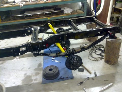 1984 Ford Bronco - Vehicle chassis undergoing a rebuild, showing suspension components and brake assembly.
