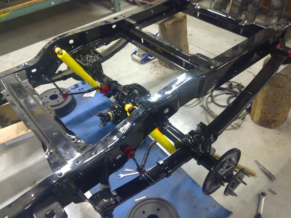 Black vehicle chassis with yellow shock absorbers during rebuild