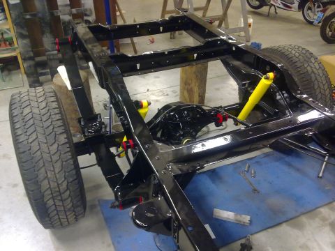 1984 Ford Bronco - The chassis of a vehicle is shown with suspension components and tires, undergoing maintenance or rebuild.
