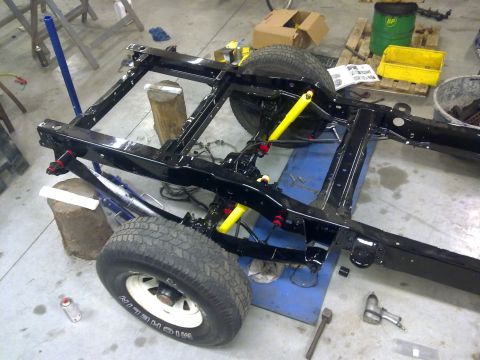 1984 Ford Bronco - Vehicle chassis undergoing a rebuild, with visible suspension components and tires.