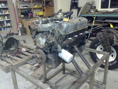 1984 Ford Bronco - Engine on a stand in a workshop setting, with other parts visible.