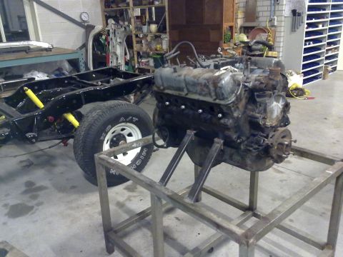 1984 Ford Bronco - The chassis and engine of a vehicle are shown in a workshop environment, possibly undergoing repair or restoration.